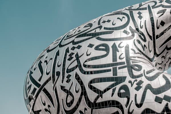 Close-up of the Museum of the Future in Dubai featuring stunning Arabic calligraphy under a blue sky.