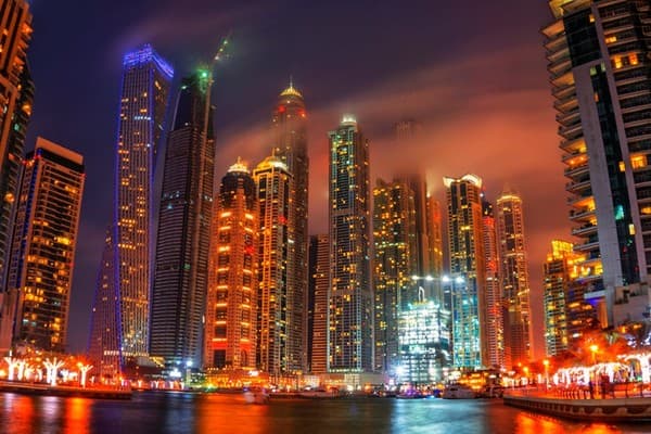 Stunning night view of Dubai Marina, featuring illuminated skyscrapers reflecting on water, showcasing urban architecture.