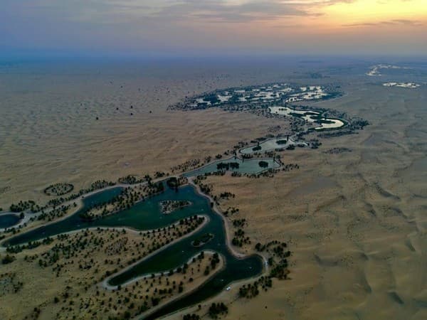 Breathtaking aerial view of the scenic Al Qudra Lake in Dubai at sunset, with winding waterways.