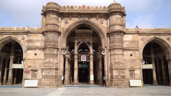 Explore the intricate architecture of a historical mosque in Ahmedabad, India, showcasing its majestic arched entrance.
