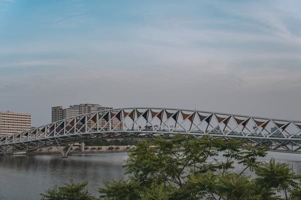 Stylish pedestrian bridge spanning the Sabarmati River with urban skyline in Ahmedabad, India.