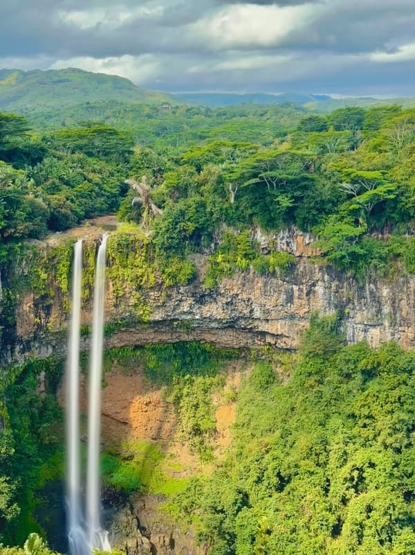 A large waterfall in the middle of a lush green forest