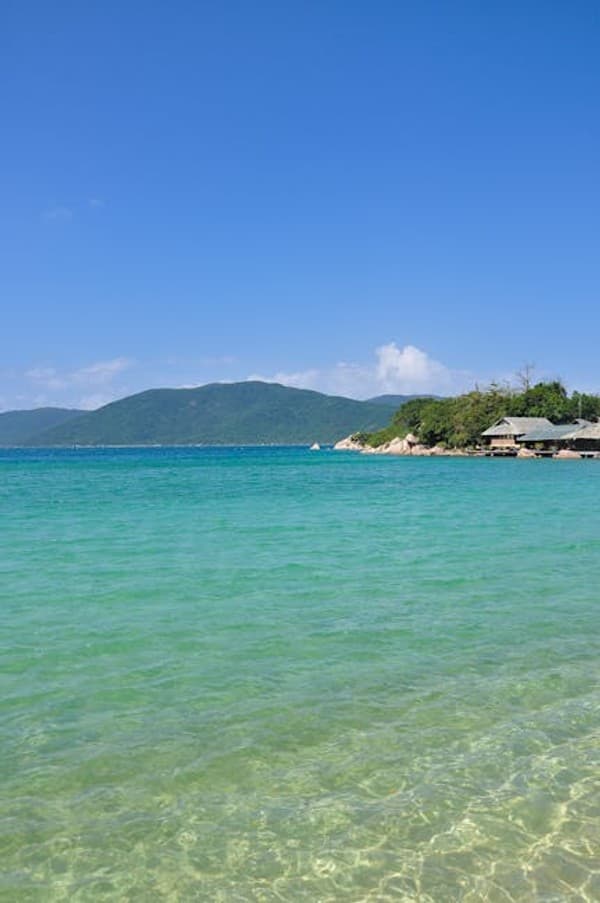 Discover the serene beauty of a pristine beach in Khánh Hòa, Vietnam, with turquoise waters and a vibrant blue sky.