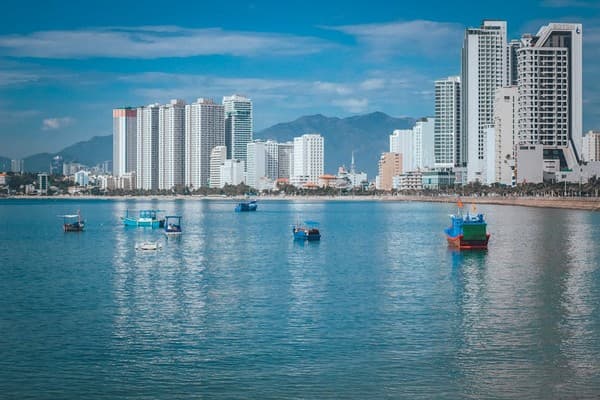Stunning view of Nha Trang skyline with boats on calm blue waters under a clear sky.