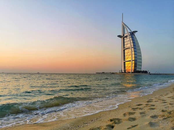 A stunning sunset view of Burj Al Arab from Jumeirah Beach, Dubai with gentle waves and golden sands. A stunning sunset view of Burj Al Arab from Jumeirah Beach, Dubai with gentle waves and golden sands.