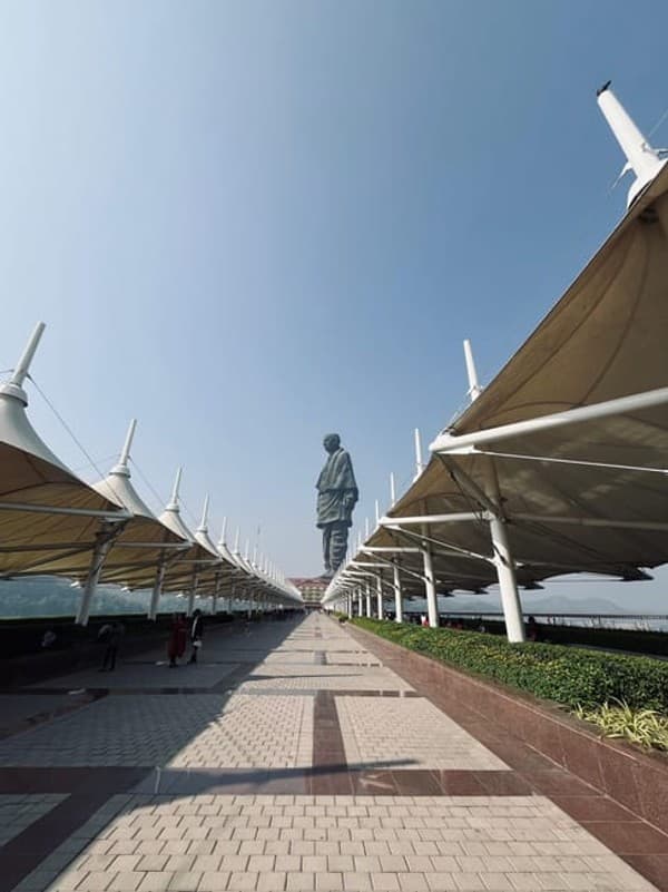 Iconic Statue of Unity in Kevadia, India, framed by architectural canopies under a clear sky. Iconic Statue of Unity in Kevadia, India, framed by architectural canopies under a clear sky.